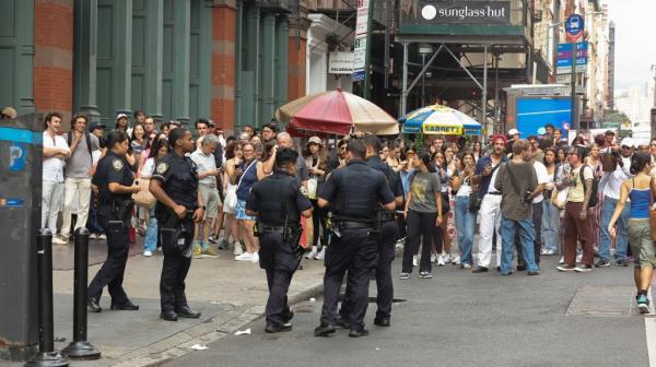 A photo of a large crowd lining the sidewalk and street outside Zara in Soho.